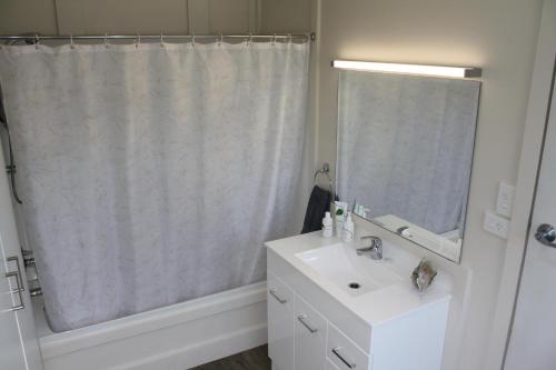 uma casa de banho branca com um lavatório e um espelho em Classic A-frame on Milford em Te Anau