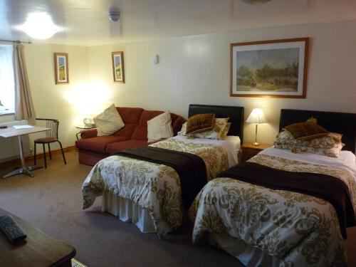um quarto de hotel com duas camas e um sofá em Oakenholt Farm Bed and Breakfast em Flint