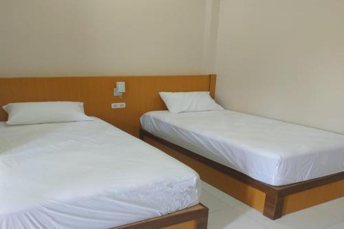 two beds sitting next to each other in a room at Nietsa Guest House Palu RedPartner in Palu