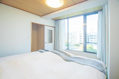 a bedroom with a bed and a large window at AMP FLAT Nishijin 5 in Fukuoka