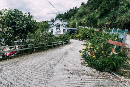 a house on a road with flowers in front of it at Amazing Grace Lodge in Kundasang