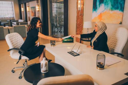 two women sitting at a table with a book at Jewel Green Mountain Hotel in Cairo