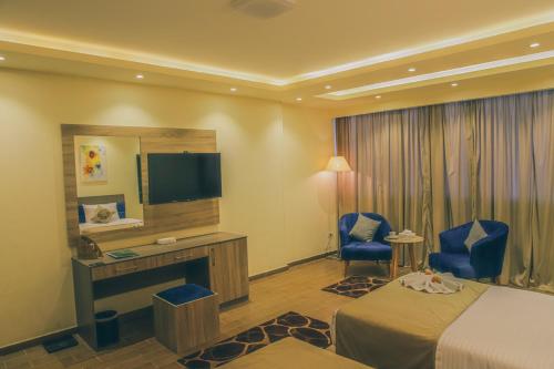 una camera d'albergo con letto, scrivania e TV di Jewel Green Mountain Hotel a Il Cairo