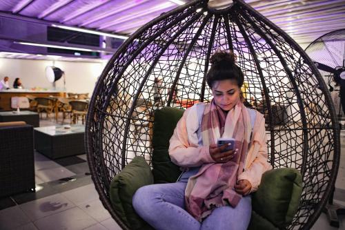 a woman sitting in a hanging chair looking at her cell phone at Jewel Green Mountain Hotel in Cairo
