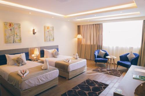 a hotel room with two beds and a chair at Jewel Green Mountain Hotel in Cairo