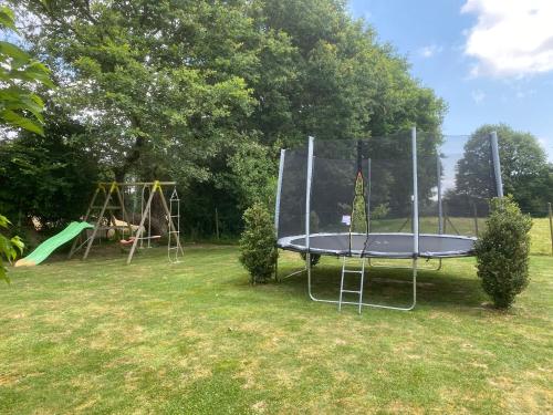 an empty trampoline in a yard with a playground at Grange de la Menagerie in Mouilleron-le-Captif