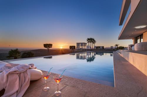 two wine glasses sitting next to a swimming pool at Eden Roc in Pòrtol