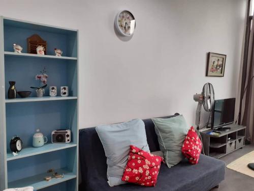 uma sala de estar com um sofá azul com almofadas vermelhas em Empire Damansara Homes by Cities Homes Malaysia em Petaling Jaya
