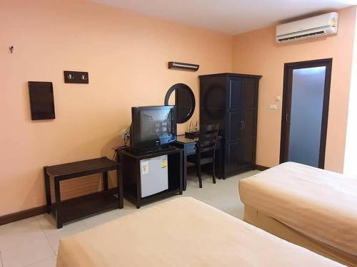 ein Hotelzimmer mit einem Bett, einem TV und einem Schreibtisch in der Unterkunft The Victory Hotel in Ban Muang Daeng