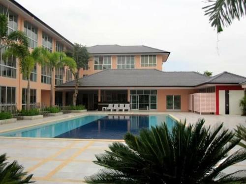 un bâtiment avec une piscine en face d'un bâtiment dans l'établissement The Victory Hotel, à Ban Muang Daeng