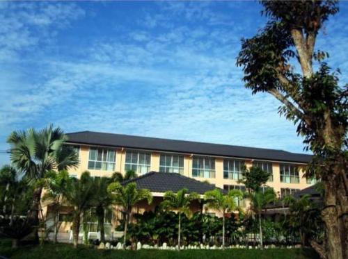 a large building with palm trees in front of it at The Victory Hotel in Ban Muang Daeng
