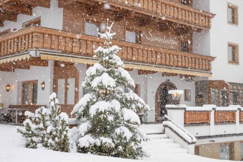 un albero di Natale coperto di neve di fronte a un edificio di Hotel Pension Sonnleiten a Tux