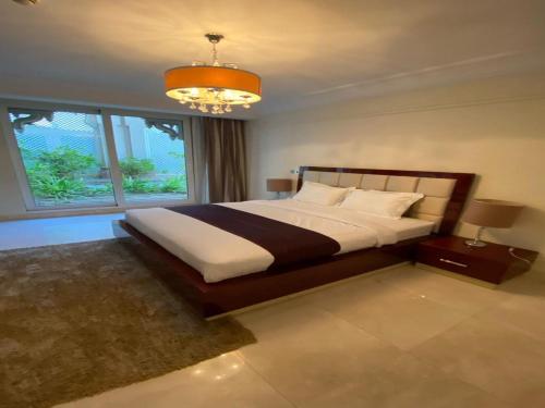 a bedroom with a large bed and a chandelier at OYO 603 Home Taj Grandeur 2br in Dubai