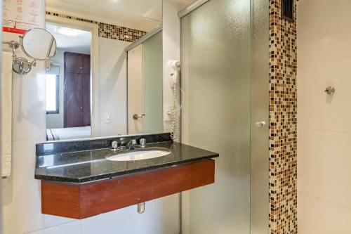 a bathroom with a sink and a mirror at Park Tower Campinas Residence by Nacional Inn in Campinas