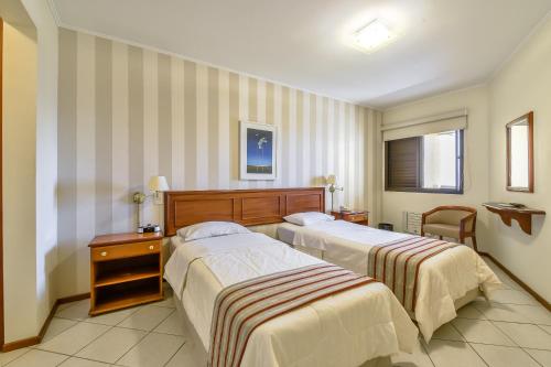 a hotel room with two beds and a table at Park Tower Campinas Residence by Nacional Inn in Campinas