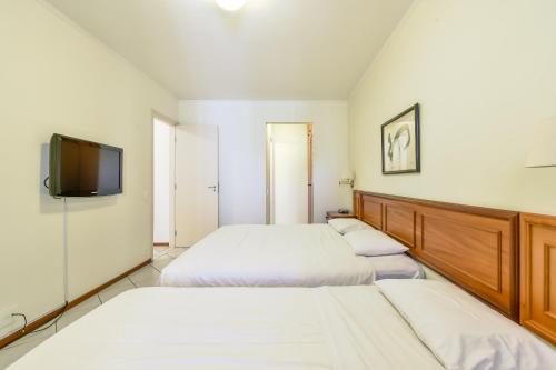 a bedroom with two beds and a flat screen tv at Park Tower Campinas Residence by Nacional Inn in Campinas