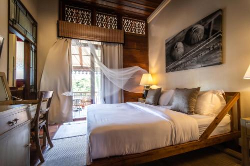 um quarto com uma cama, uma secretária e uma janela em Punyashthiti villa em Chanthaburi