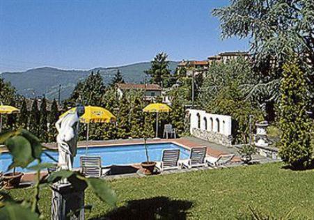 una piscina con sillas y sombrillas en un patio en La Comanella, en Comano