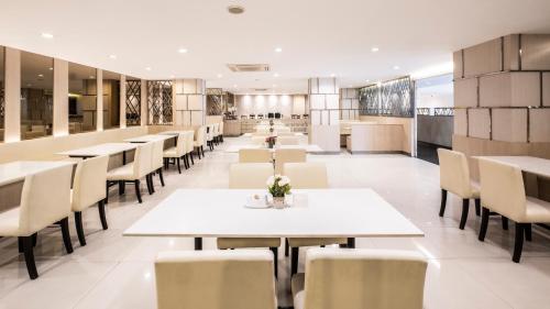 a dining room with white tables and chairs at The Airport Courtyard Suvarnabhumi Airport in Bangkok