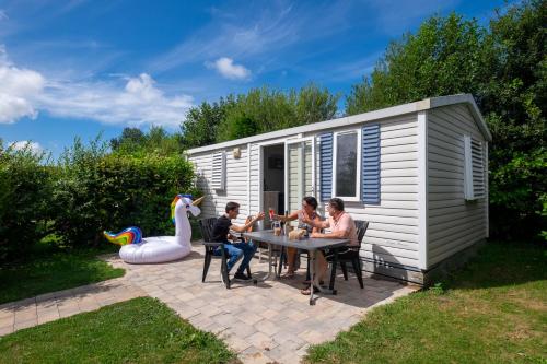 a group of people sitting at a table in front of a caravan at Vakantiepark Koningshof in Rijnsburg
