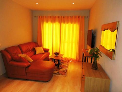 a living room with a red couch and yellow curtains at Magnifique Appartement au coeur de la Senegambia Kololi in Banjul
