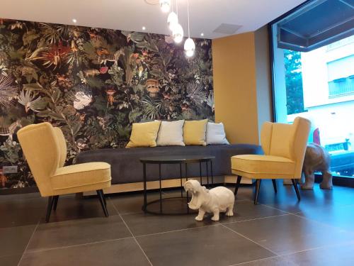 ein Wohnzimmer mit einem Sofa, 2 Stühlen und einem Hund in der Unterkunft Prince Albert Lyon Bercy in Paris