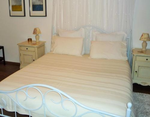 a white bed with white pillows and two night stands at Chez Edèll in Monpazier