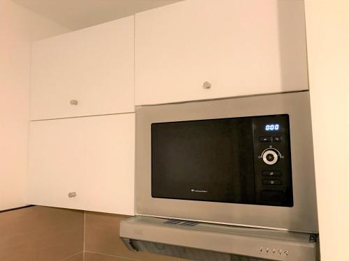 a television in a room with white cabinets at Bel appartement design tout confort (Parking Gratuit) à 10 minutes de Bordeaux in Cenon