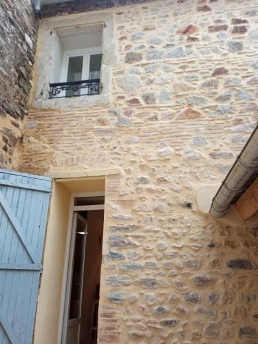 - un bâtiment en pierre avec une fenêtre et un balcon dans l'établissement Appartements Aux Portes d'Alès - Centre Ville, à Alès
