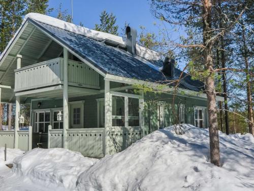 ein schneebedecktes Haus mit einem Schneehaufen in der Unterkunft Holiday Home Huuhkalinna by Interhome in Syöte