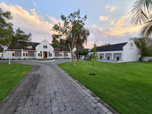 a cobblestone driveway in front of a white building at Uitsig Boutique Hotel in Welkom