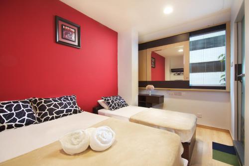 a bedroom with two beds and a red wall at Tai Hoe Hotel in Singapore