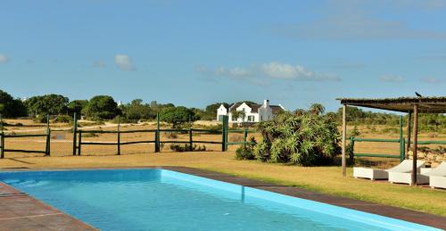 a swimming pool in a yard with a house in the background at De Hoop Collection - Vlei Cottages in De Hoop Nature Reserve