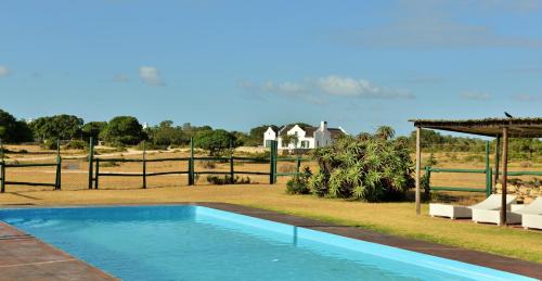 una piscina in un cortile con una casa sullo sfondo di De Hoop Collection - Vlei Cottages a De Hoop Nature Reserve