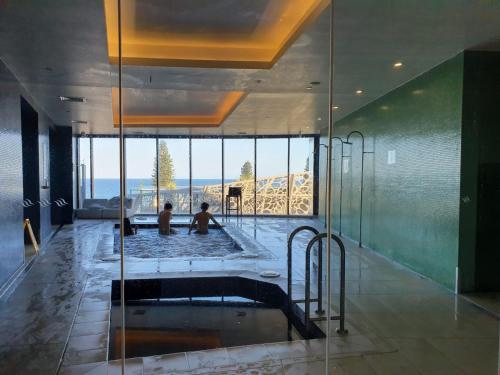 two people sitting in a hot tub in a room with glass at High-End Apartment in the Soul of Surfers Paradise in Gold Coast