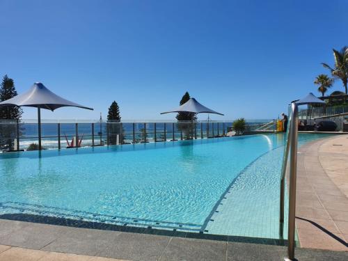 a large swimming pool with a view of the ocean at High-End Apartment in the Soul of Surfers Paradise in Gold Coast
