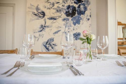 a table with plates and glasses and a vase with flowers at De Oude Pastorie Macharen in Macharen