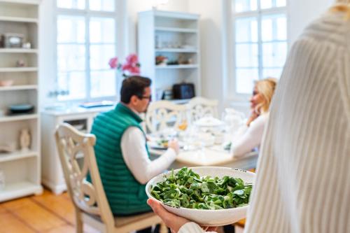 a man and woman sitting at a table with a bowl of greens at Lovecký zámeček pod Milešovkou in Teplice