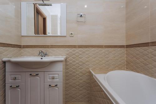 uma casa de banho com um lavatório, uma banheira e um espelho. em Luxury Apartment em Sumy