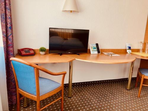 a room with a desk with a television and a chair at Akzent Congresshotel Hoyerswerda in Hoyerswerda