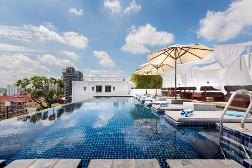 ein Pool mit Liegestühlen und einem Sonnenschirm auf einem Gebäude in der Unterkunft PATIO Hotel & Urban Resort in Phnom Penh