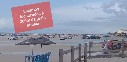a sign on a beach with chairs and an umbrella at Pousada Aconchego in Salinópolis