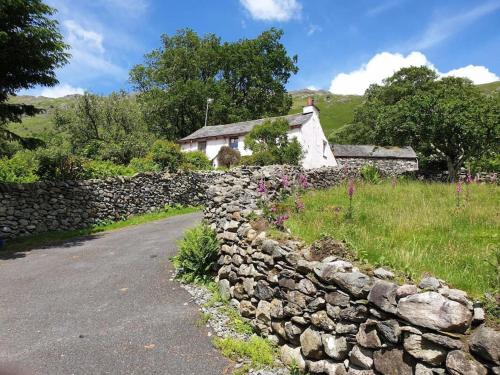 a stone wall next to a house and a road at Pye Howe in Ambleside