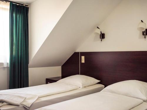 two beds in a bedroom with a sloped ceiling at Hotel Mużakowski in Łęknica