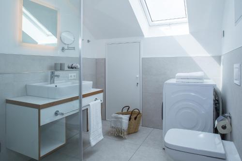 biała łazienka z toaletą i umywalką w obiekcie Upstalsboom Residenzen Strandidyll w Trassenheide