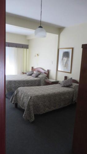 a bedroom with two beds and a pendant light at Hotel Principe in Buenos Aires