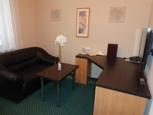 a office with a couch and a desk and a chair at Hotel Vacek Pod Věží in Hradec Králové