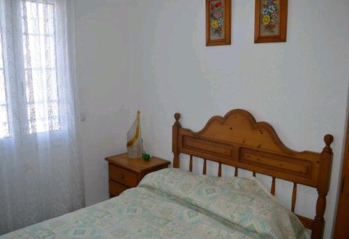a bedroom with a wooden bed and a dresser and a window at R116 Casa adosada con piscina privada en Cunit in Cunit