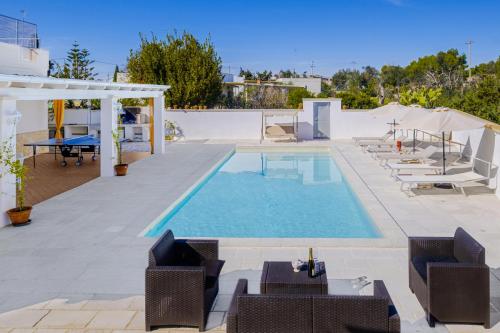 a swimming pool with chairs and a table and a table at Villa Christelle Luxury Pescoluse by HDSalento in Marina di Pescoluse