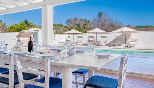 una mesa de comedor con una botella de vino junto a la piscina en Villa Christelle Luxury Pescoluse by HDSalento, en Marina di Pescoluse